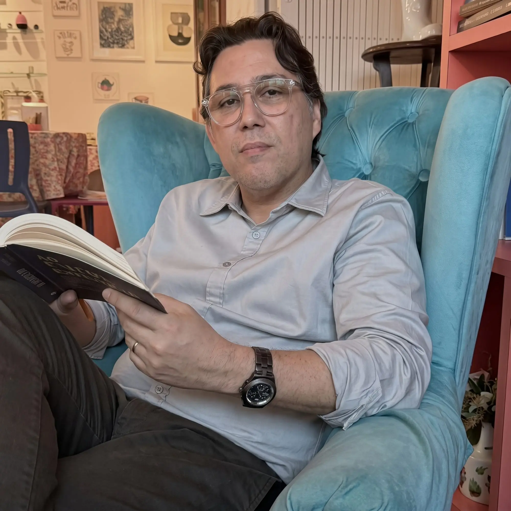 Fabio Blanco lendo em uma poltrona, cercado de livros