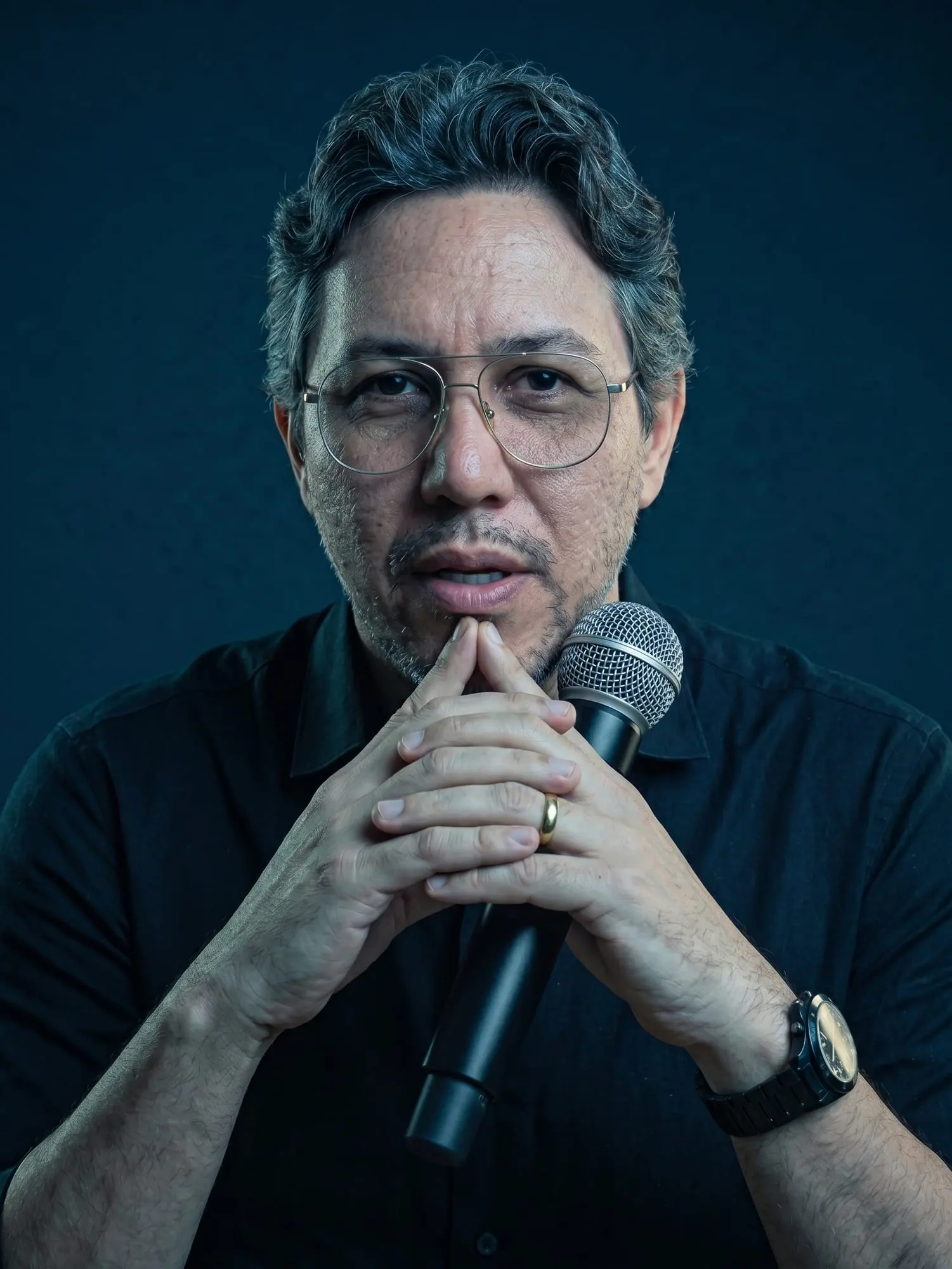 Fabio Blanco, professor de oratória, com as mãos unidas segurando um microfone